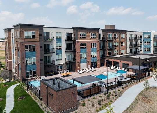 A large apartment complex with a pool and a small building in front.