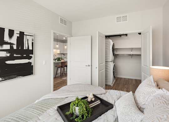 A bedroom with a bed, a tray with a plant on it, and a painting on the wall.