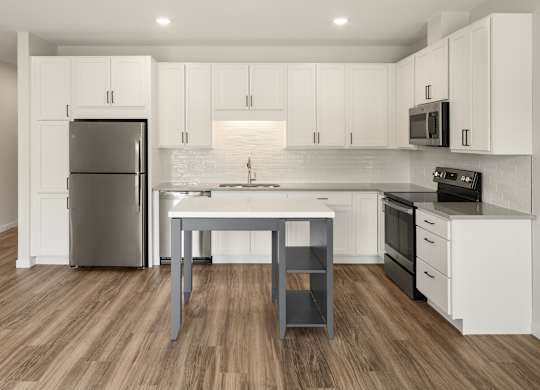 A modern kitchen with white cabinets and a wooden floor.