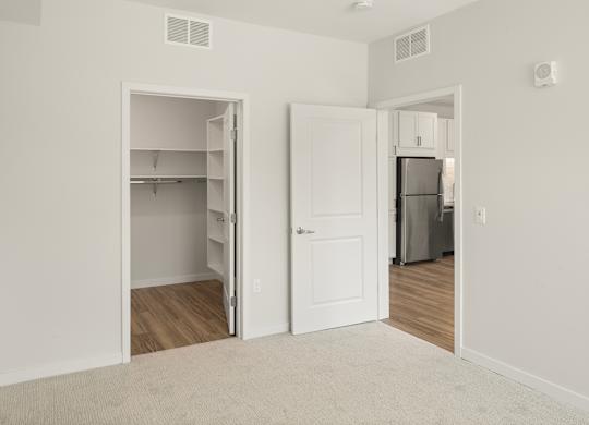A white room with a doorway leading to a kitchen.