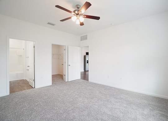 A room with a ceiling fan and carpeted floor.