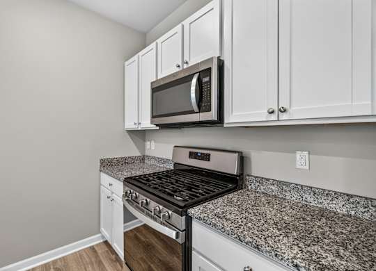 A kitchen with a granite countertop and white cabinets.