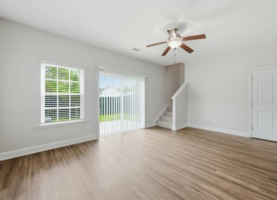 A room with a ceiling fan and wooden flooring.