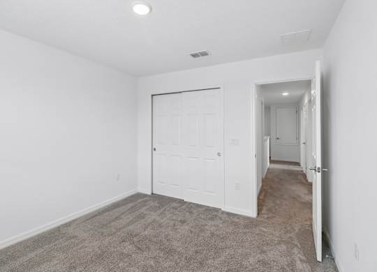 A white bedroom with a carpeted floor and a white door.
