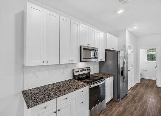 A kitchen with white cabinets and a granite countertop.
