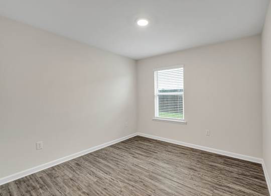 A room with a window and wooden flooring.