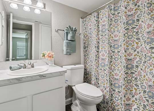 A white bathroom with a floral shower curtain.