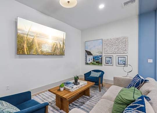 A living room with a blue couch, a wooden coffee table, and a painting on the wall.