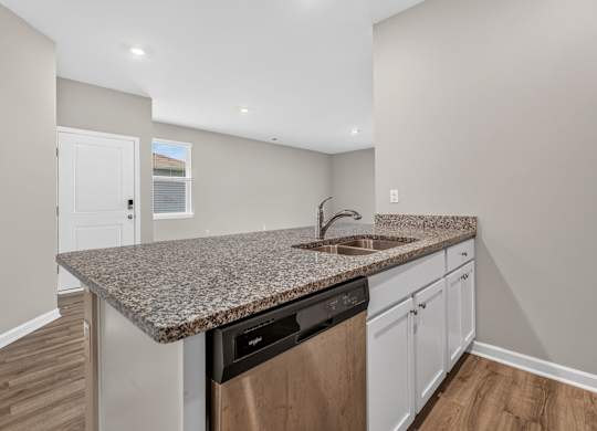 A kitchen with a granite countertop and a black dishwasher.