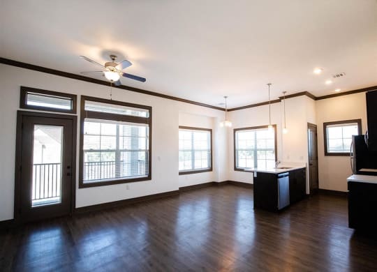 an empty living room with wood floors and a ceiling fan