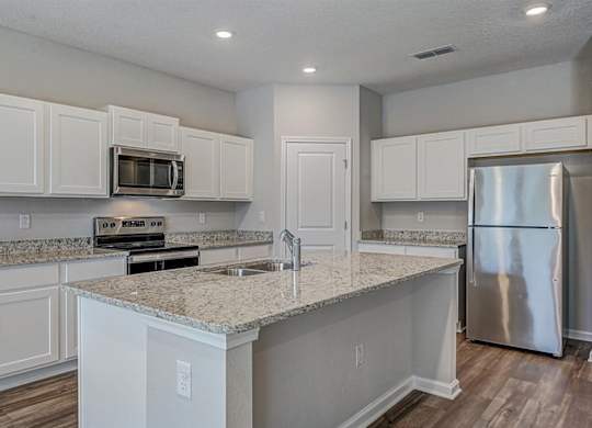 Modern kitchen with white cabinets, granite countertops, stainless steel appliances, and a central island.