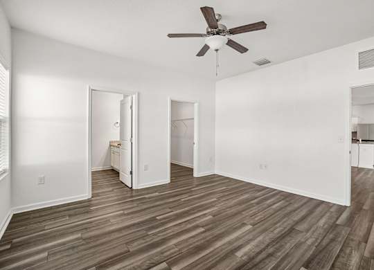 A room with a ceiling fan and wooden flooring.