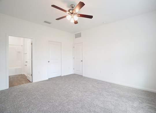 A room with a ceiling fan and carpeted floor.