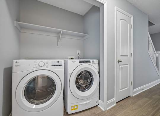 Two white front load washing machines in a laundry room.