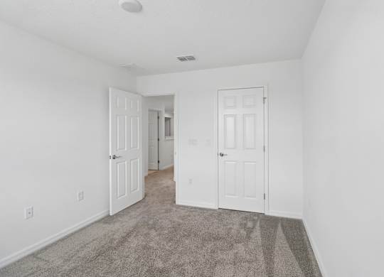 A room with two white doors and a carpeted floor.