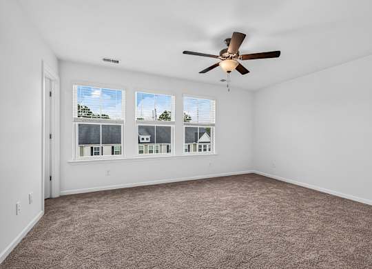 A room with a ceiling fan and carpeted floor.