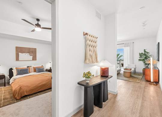 A bedroom with a bed, nightstand, and a wall hanging.
