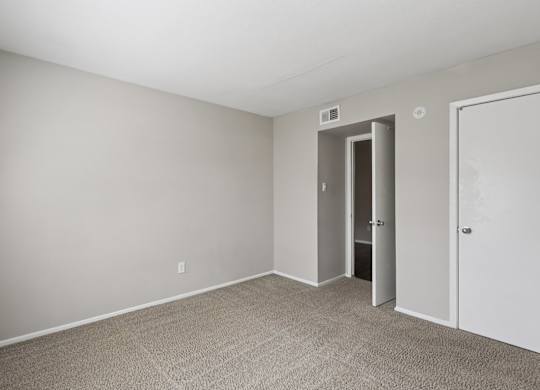 A room with a carpeted floor and two doors.