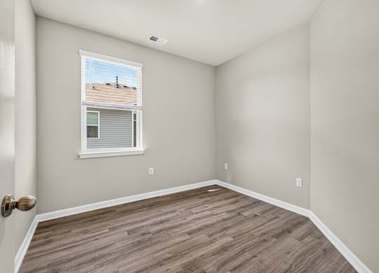 A room with a window and wooden flooring.