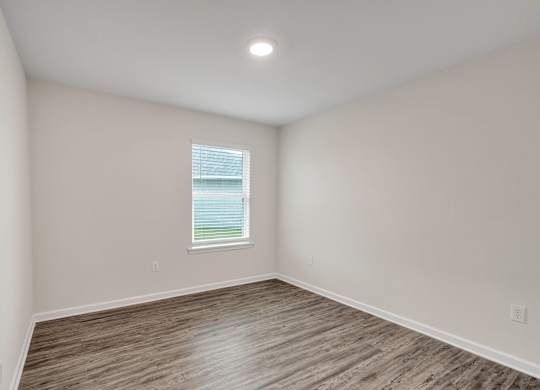 A room with a window and wooden flooring.