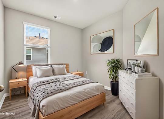 A bedroom with a bed, nightstand, and a potted plant.