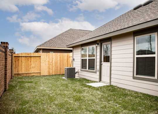 a home with a wood fence and grassy yard
