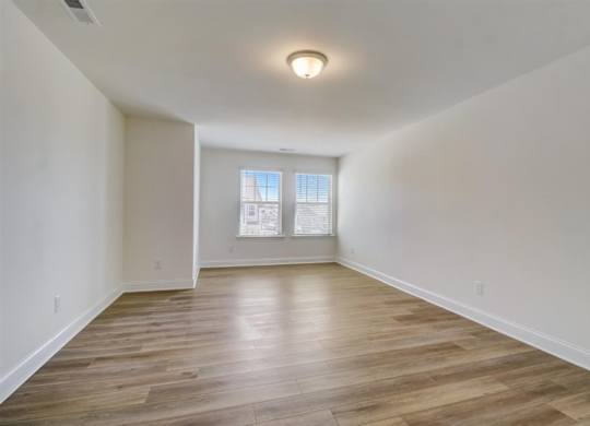 a bedroom with hardwood floors and a large window