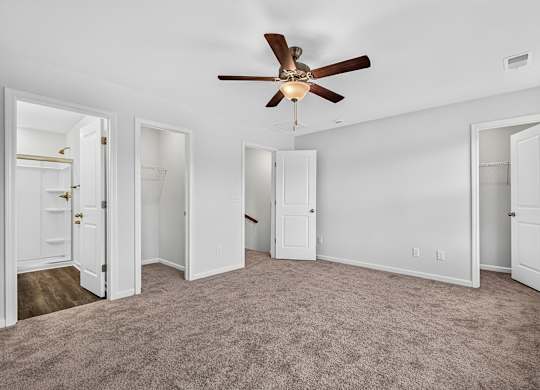 A room with a ceiling fan and carpeted floor.