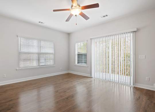 Harris Trail Luxury Townhomes for rent Richmond Hill, GA photo of an empty living room with a ceiling fan and a window