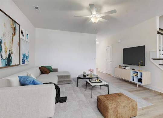 A living room with a couch, chair, ottoman, and a television.