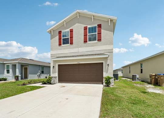 A two-story house with a garage is in front of other houses.