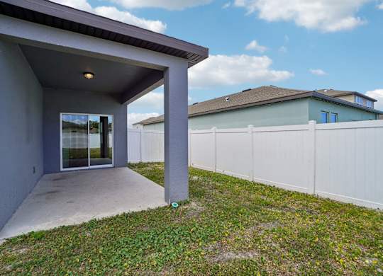 A grey house with a white fence in the background.