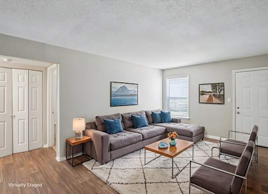 A living room with a grey couch, a coffee table, and a chair.