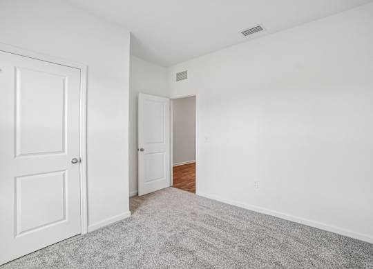 A room with a white door and a carpeted floor.