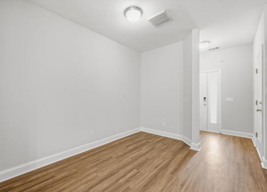 A room with wooden flooring and white walls.