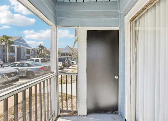 A view of a balcony with a closed door and a railing.