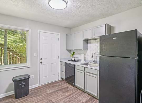 A kitchen with a black refrigerator and white cabinets.