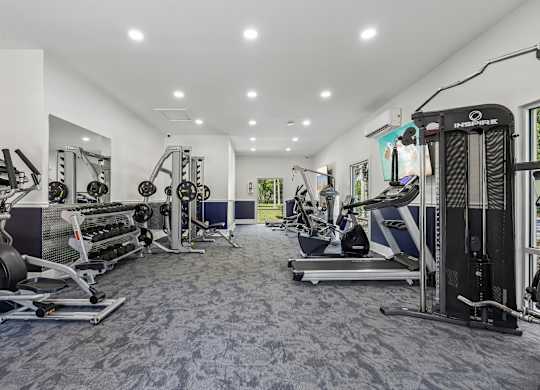 A spacious gym with a variety of equipment including treadmills, weight machines, and free weights.
