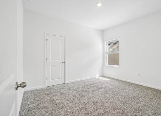 A room with a carpeted floor and a door.