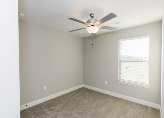 an empty room with a ceiling fan and a window