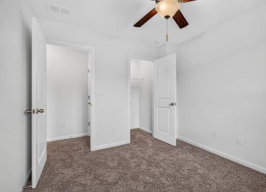 A room with a ceiling fan and carpeted floor.