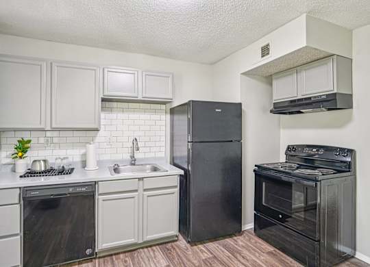 A kitchen with black appliances and white cabinets.