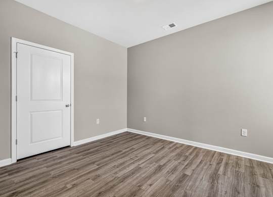 A room with a white door and wooden flooring.