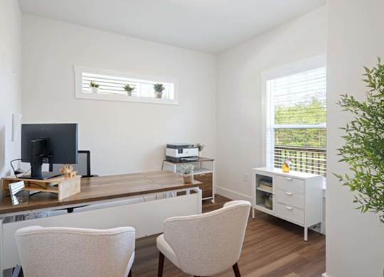 A room with a desk, chairs, and a printer.