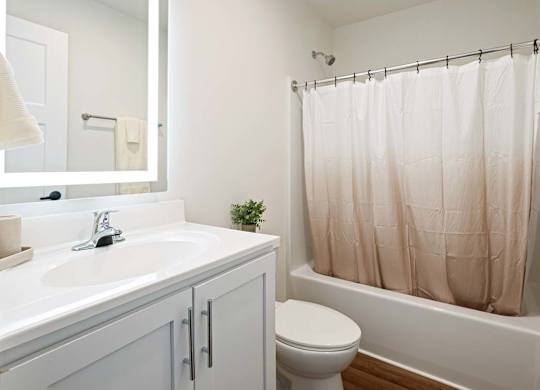 A white bathroom with a toilet, sink, and shower.