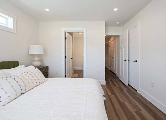 A bedroom with a large bed and a lamp on the nightstand.