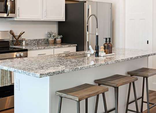 A kitchen with a granite countertop and bar stools.