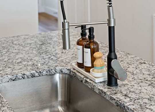 A kitchen sink with a black faucet and soap dispenser.