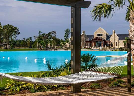 Pet-Friendly Homes for Rent in Humble, TX - Edgewater at the Lagoon - Pool with a Hammock in Shaded Area, and Beautiful Landscaping