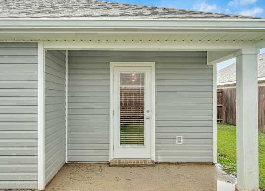 A small house with a grey siding and a white door.